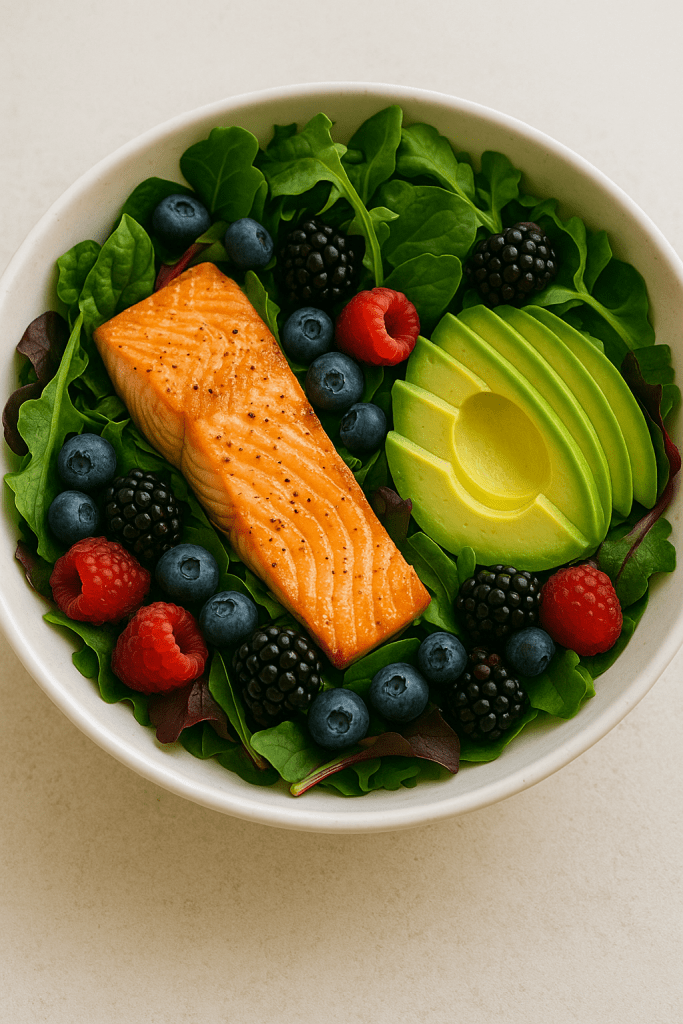 Anti-inflammatory salad with salmon, avocado, mixed greens, and fresh berries.